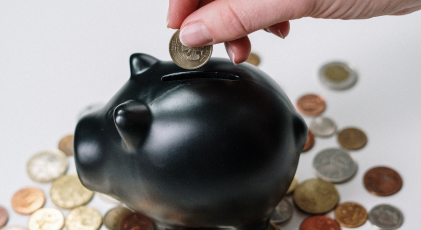 a hand putting a coin in a piggy bank